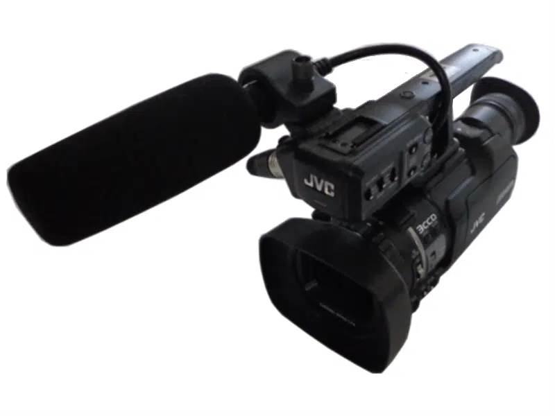 JVC GY-HM150E professional video camera with a large attached microphone, displayed at an angle on a plain white background. High-quality camcorder available for rent.