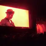 Large outdoor screen at Lichtfest 2014 displaying a close-up of a musician in a hat performing on stage under red-orange lighting, with an audience gathered below at night during an outdoor concert.