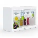 A white display box showcases three bottled fruit drinks with visible fruit slices and water splashes, while a man in a dark shirt gestures toward the beverages. The scene is presented on the 32 Zoll Full HD Hypebox Touch by Screensource (model HBT3210L), with vibrant, colorful graphics highlighting the interactive screen’s clarity.