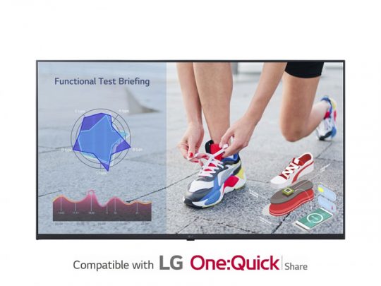 A large monitor screen displays colorful data charts and a photo of hands tying vibrant sneakers, highlighting LG One:Quick Share compatibility for seamless wireless sharing and presentations.