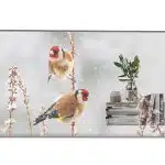 Product image shows a modern wall-mounted digital display featuring two colorful birds perched on dry stems in a snowy winter landscape. The screen is positioned above a tidy shelf with stacked books, a small potted plant in a vase, and minimalist decorative items, creating a cozy and stylish home decor setting. Ideal for digital art frames or smart displays.