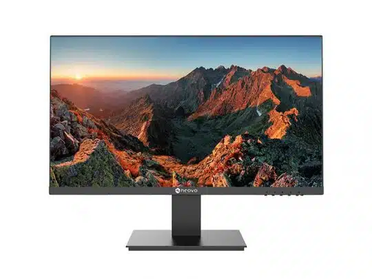A flat-screen computer monitor with thin bezels and a rectangular stand displays a vivid sunrise mountain landscape, with sunlight illuminating rocky peaks and valleys. The screen shows vibrant colors, highlighting the monitors clarity and display quality.