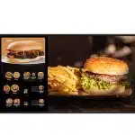 Digital menu board showing burger options and prices on the left, with a close-up of a classic cheeseburger topped with lettuce and tomato, served with fries on a wooden tray, on the right. Perfect for restaurant digital signage and burger menu advertising.