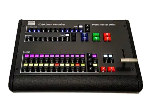 Schwarzer Barco EC-30 Event Controller aus der Event Master Serie, ideal zum Kaufen oder Mieten; das Gerät zeigt mehrere Reihen farbiger Tasten, beschriftete Bereiche für Destinations, Layers und Assign sowie einen silbernen Steuerhebel auf der rechten Seite - perfekt zur professionellen Veranstaltungssteuerung.