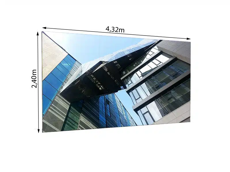 Moderne Glas- und Stahlfassade mit kantigem Design, fotografiert von unten vor blauem Himmel. Im Vordergrund ist eine große LED Wand mit den Maßen 4,32m x 2,40m zu sehen; es handelt sich um das Modell "LEDCON SL-3.75SI" mit 3,75mm Pixelabstand zum Mieten. Die LED-Wand ist deutlich gekennzeichnet mit ihren Abmessungen: 2,40m Höhe und 4,32m Breite.
