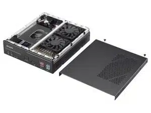 Der LOG Compact Media PC Mini UHD 4K V3 zur Miete ist auf dem Bild ohne seine schwarze Metall-Abdeckung zu sehen. Sichtbar sind die internen Komponenten wie eine Dual-Lüfter-Grafikkarte und gut erreichbare frontseitige Anschlüsse auf dem Mainboard. Die Abdeckung liegt neben dem geöffneten Mini-PC.