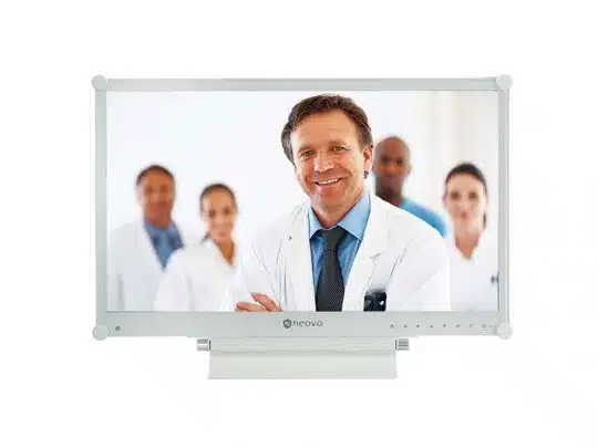 Computerbildschirm zeigt einen lächelnden Arzt im weißen Kittel und mit Krawatte, der mit drei medizinischen Kollegen vor hellem Hintergrund steht - Symbolbild für Praxismonitor zum Mieten oder Kaufen.