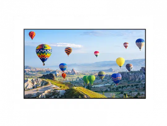 Mehrere bunte Heißluftballons schweben über einer malerischen Landschaft mit felsigen Hügeln, grünen Feldern und entfernten Bergen - das perfekte Erlebnis für eine Heißluftballonfahrt.