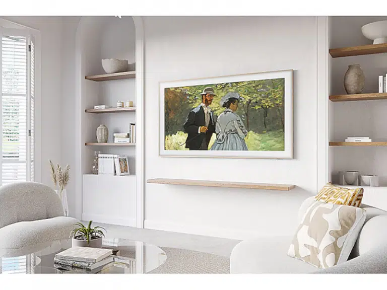 Samsung The Frame 43 Zoll 4K/UHD QLED-TV ist stilvoll an einer weißen Wand in einem modernen Wohnzimmer mit neutralen Farbtönen montiert, über einem schwebenden Regal und vor eingebauten Regalen sowie einem Glastisch - ideal zum Mieten für ein elegantes Wohnambiente.