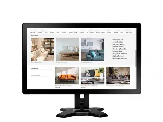 Computerbildschirm zeigt die Website "Sofas & Wohnlandschaften" mit Fotos und Beschreibungen verschiedener Ecksofas in neutralen und blauen Farbtönen; zu sehen sind moderne Sofamodelle im Online-Shop für Wohnzimmermöbel.