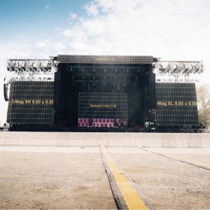 LED Wand mieten: Große Outdoor-Bühne mit schwarzen LED-Wänden, leerem abgesperrtem Bereich und gelbem Kabelschutz am Boden.
