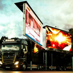 LED Wand mieten: Schwarzer Mercedes-Truck mit zwei großen LED-Werbeflächen, draußen bei bewölktem Himmel geparkt.