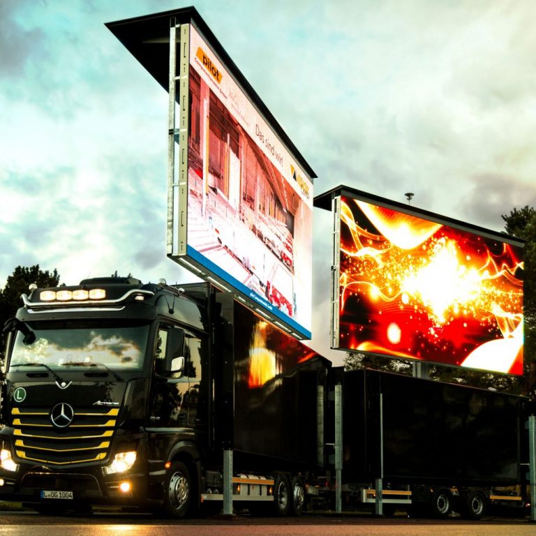 LED Wand mieten: Schwarzer Mercedes-Truck mit zwei großen LED-Werbeflächen, draußen bei bewölktem Himmel geparkt.