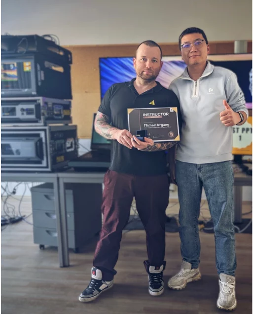 Zwei Männer mit "Instructor Michael Ingram Practitioner Level PMA Certificate" vor Regalen und Schreibtisch mit Elektronik.