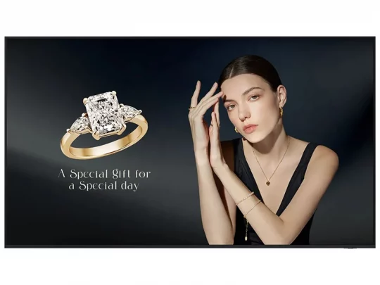 Diamantring mit Goldband, präsentiert von einer Frau in einem schwarzen Kleid vor dunklem Hintergrund. Text: Eine besondere Geschenkidee.