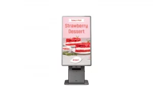 Ein digitaler Touchscreen auf einem grauen Ständer zeigt eine Werbeanzeige für „Strawberry Dessert“ mit Bildern von Erdbeer-Dessertwürfeln und einer Schaltfläche mit der Aufschrift „Order!“. Ideal für die Bestellung von „Strawberry Dessert“ über das Display; das Produkt ist gut erkennbar.