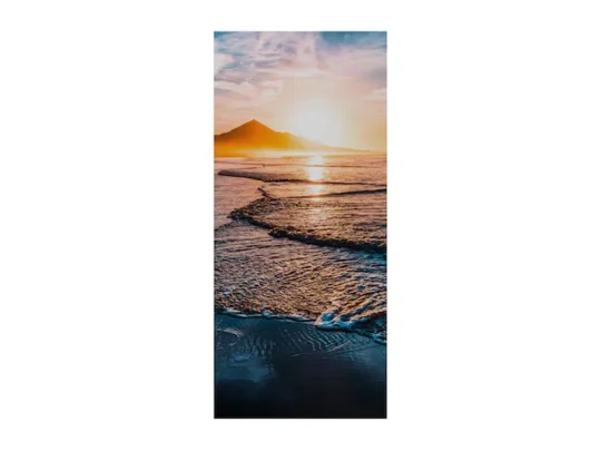 Sonnenuntergang über dem Meer mit sanften Wellen am Ufer und einem Berg im Hintergrund unter teilweise bewölktem Himmel – stimmungsvolles Landschaftsbild als Wanddekoration.